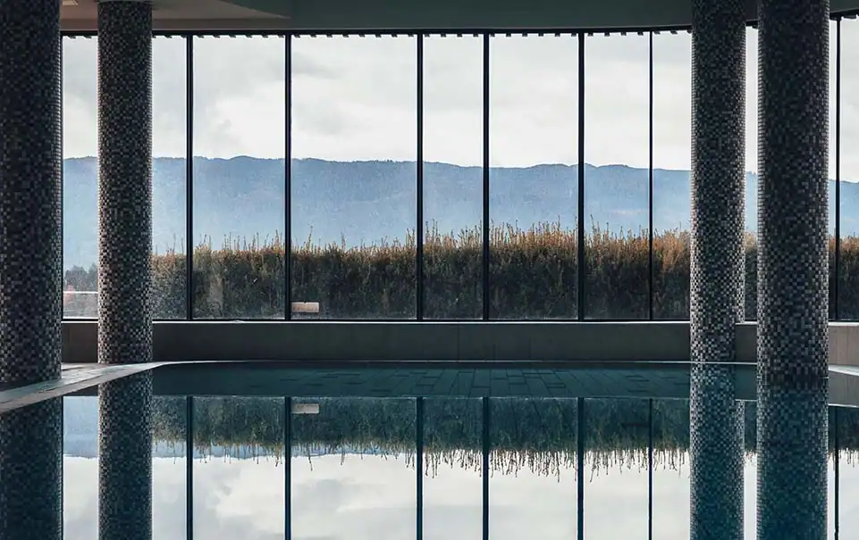 Moderner Wellnessbereich mit grossen Fensterflächen und Blick auf die umliegende Landschaft.