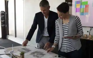 Zwei Fachleute besprechen Pläne und Unterlagen für die Planung eines Wellnessbereichs.