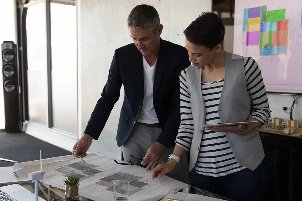 Zwei Fachleute besprechen Pläne und Unterlagen für die Planung eines Wellnessbereichs.