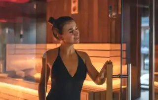 Frau entspannt in einer modernen Sauna mit warmer Beleuchtung.