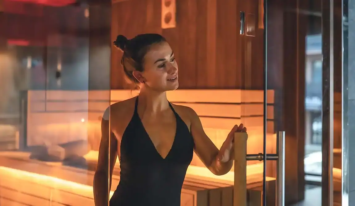 Frau entspannt in einer modernen Sauna mit warmer Beleuchtung.