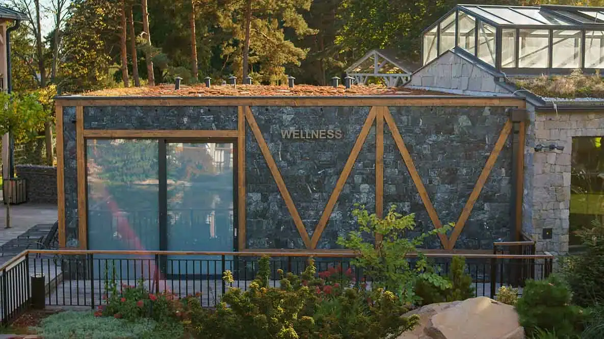 Modernes Wellnesszentrum mit Glasfassade, Naturstein und begrünter Dachfläche.