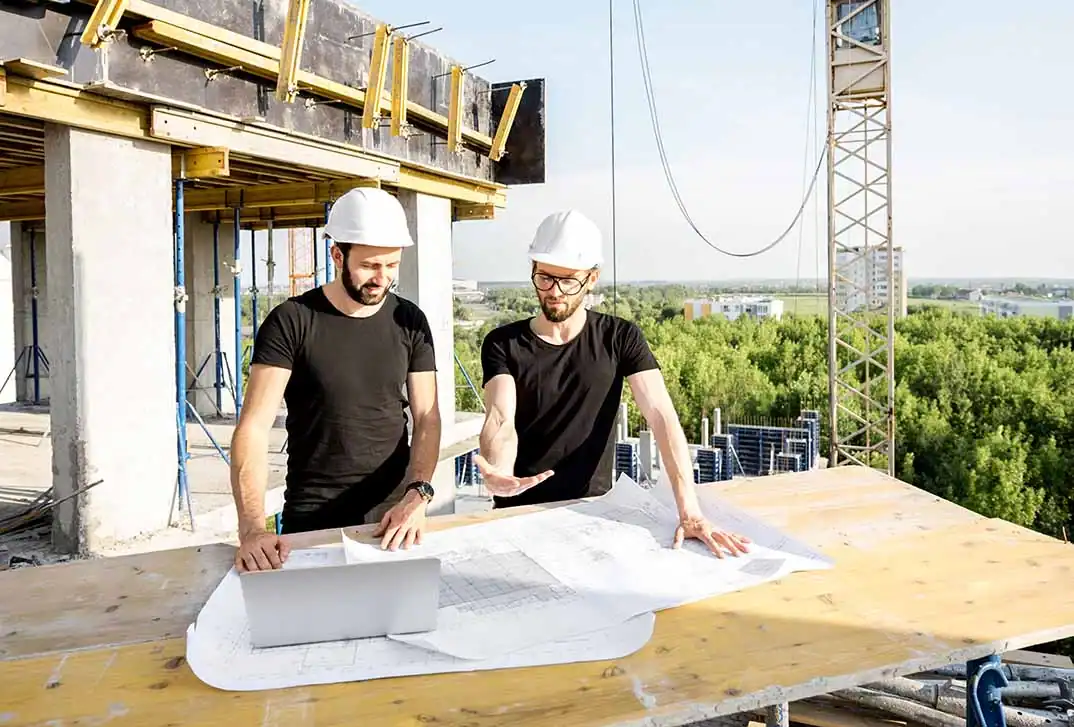 Zwei Fachplaner besprechen Baupläne auf einer Baustelle.
