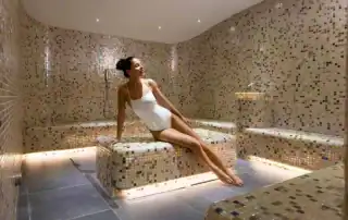 Frau entspannt in einem modernen Dampfbad mit Mosaikfliesen.