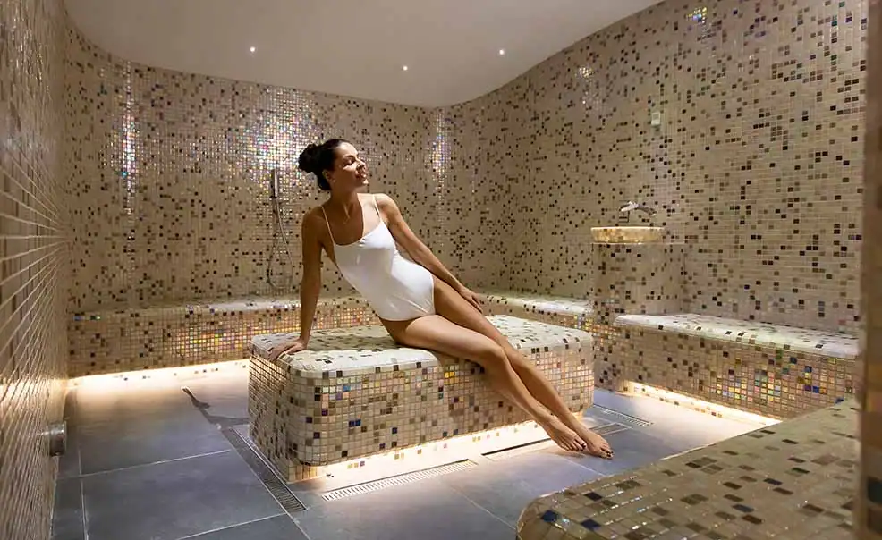 Frau entspannt in einem modernen Dampfbad mit Mosaikfliesen.
