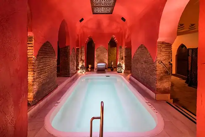 Luxuriöser Wellnessbereich mit Pool, Natursteinwänden und stimmungsvoller Beleuchtung.