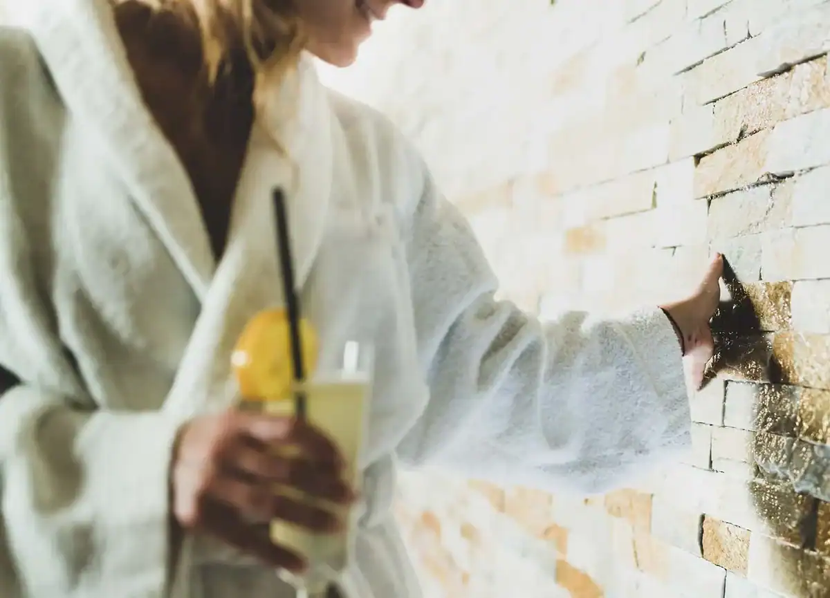 Gast berührt Natursteinwand im Wellnessbereich.