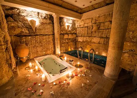 Rustikaler Wellnessbereich mit Naturstein, Holz und integriertem Whirlpool.