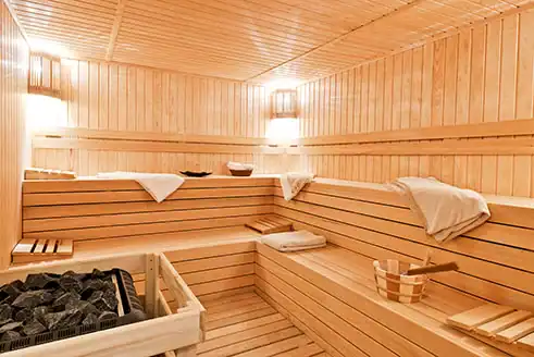 Saunabereich mit Holzliegen und warmer Beleuchtung in einer umgesetzten Wellnessanlage.