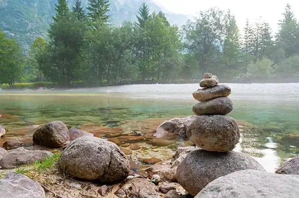 Steinmandala an einem ruhigen Flussufer.